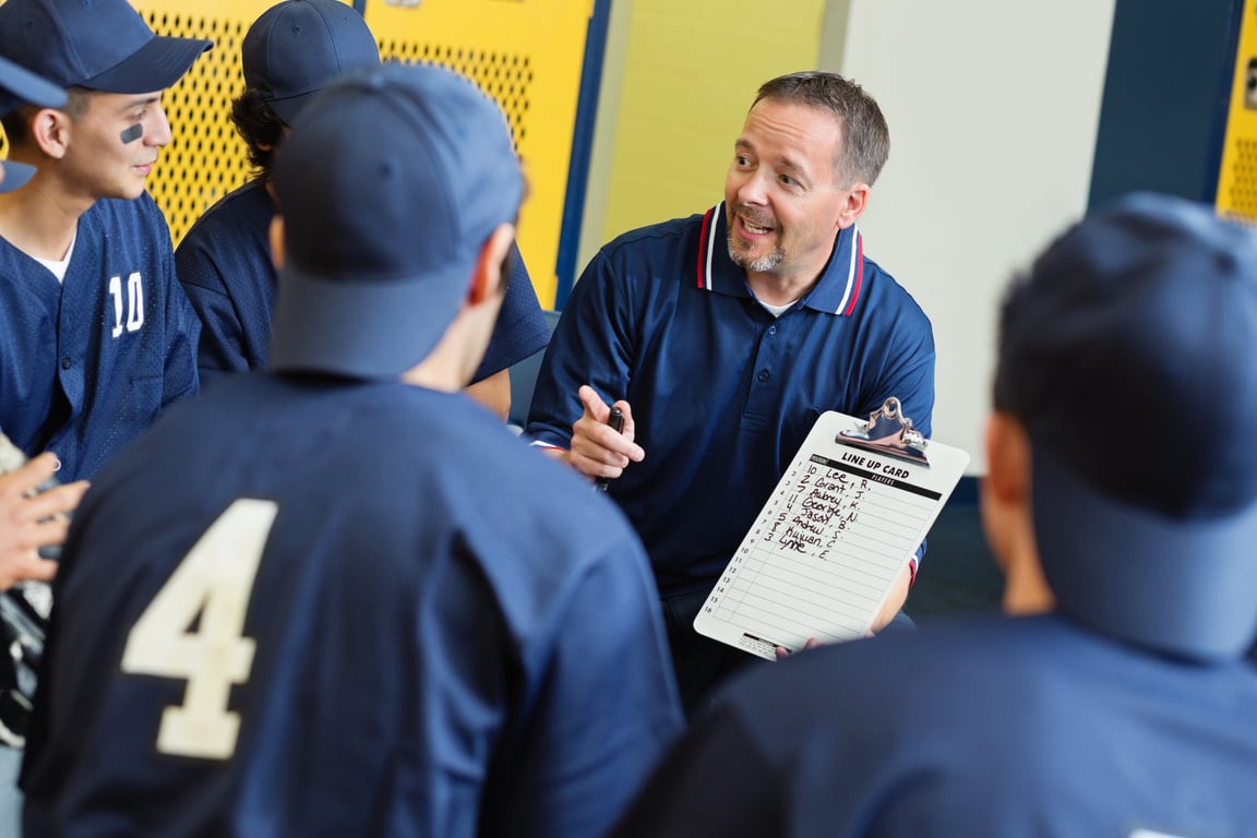 High school baseball coach with players/ locker room before game